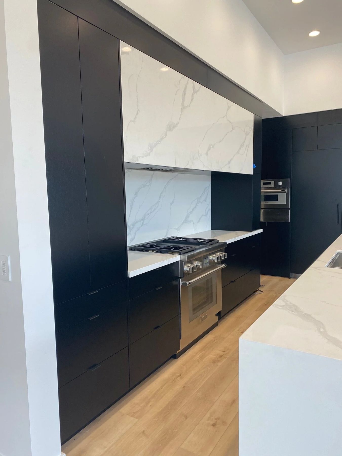 Matte black custom cabinetry with marble surround and oak floors, built by Blue Spruce Cabinet Company