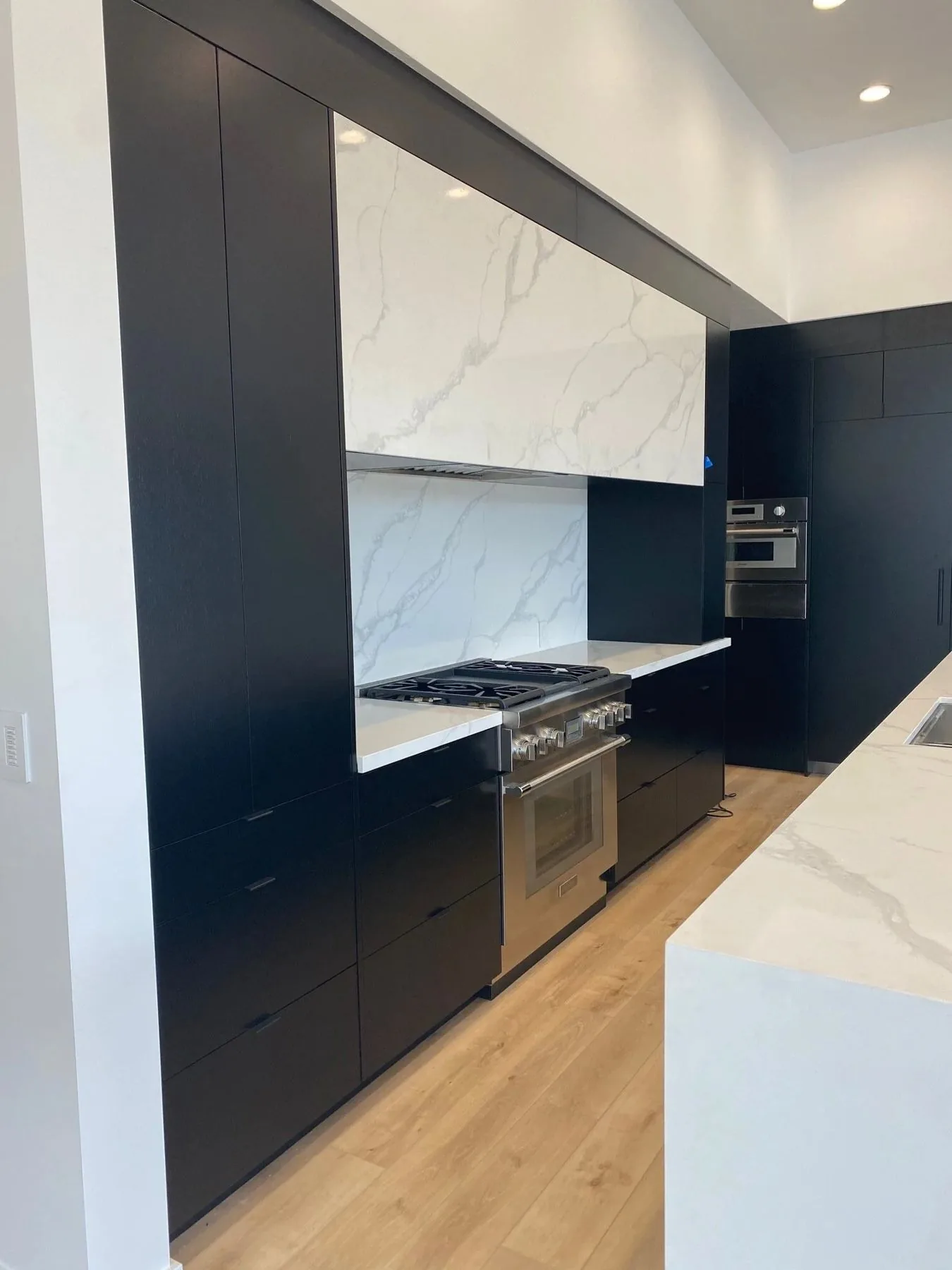 Matte black custom cabinetry with marble surround and oak floors, built by Blue Spruce Cabinet Company