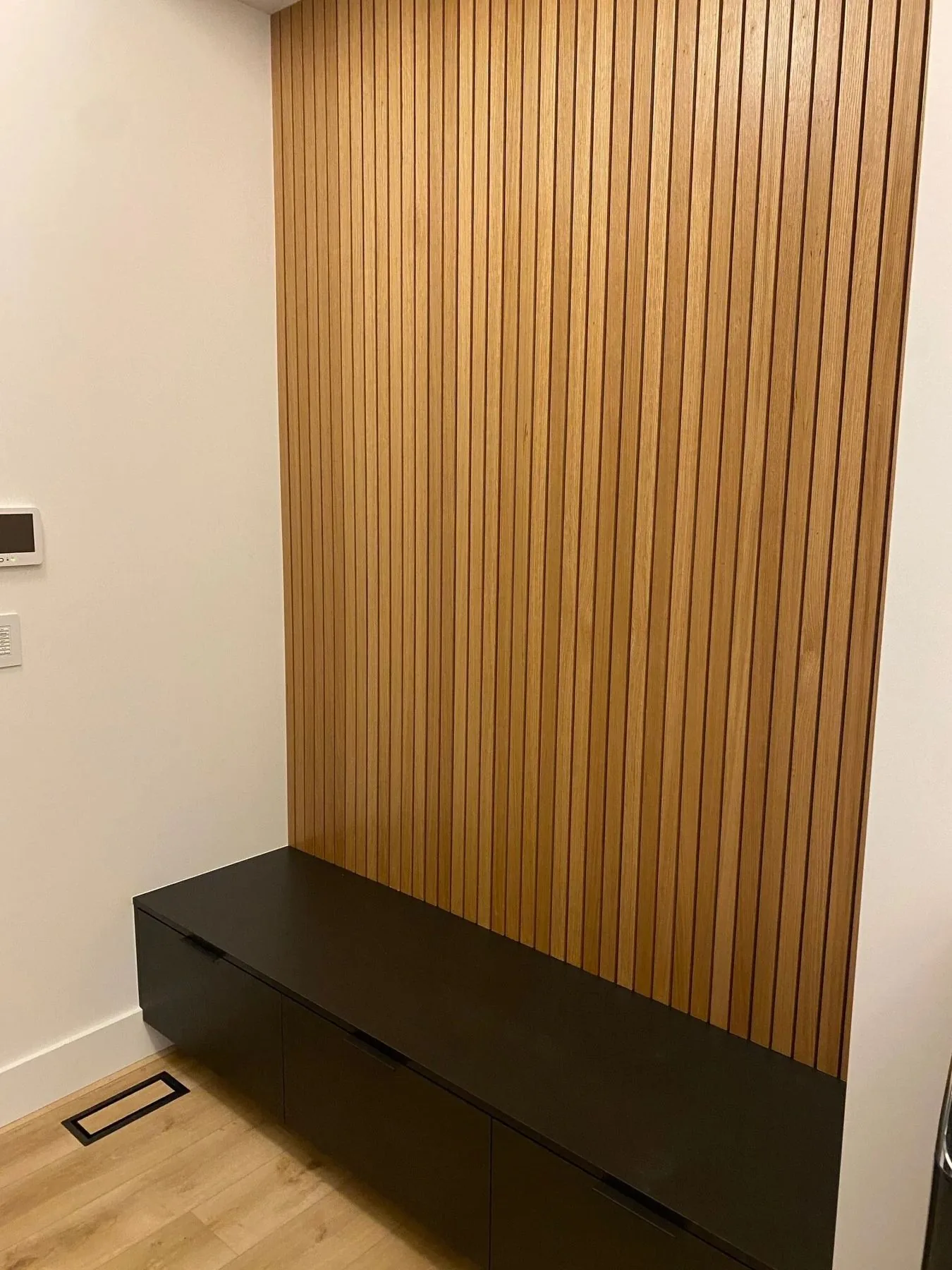 Custom wood slat wall with floating black bench