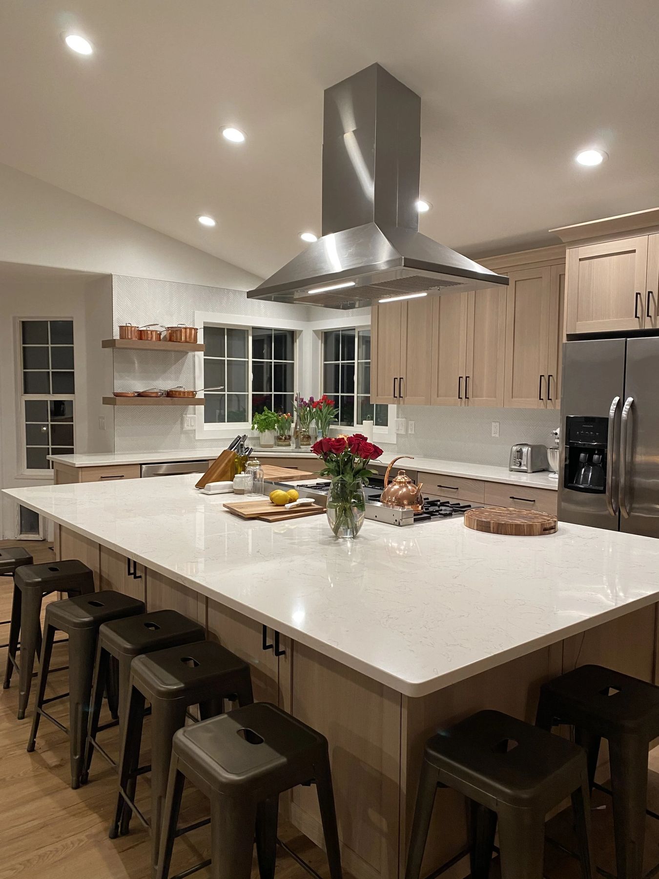 Warm residential kitchen with large island, stainless hood and open shelving