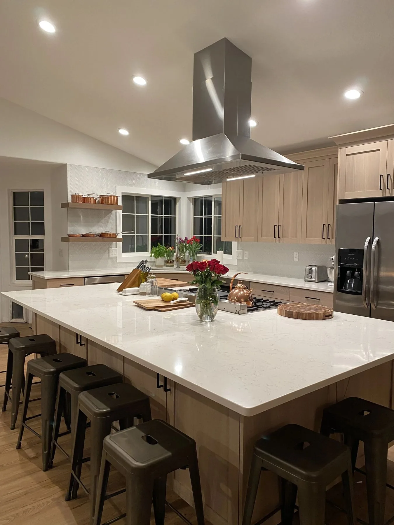 Warm residential kitchen with large island, stainless hood and open shelving